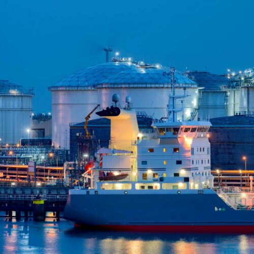 liquid natural gas storage tanks with tanker ship in foreground